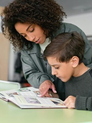 pexels photo 8342281 8342281 A woman helps a boy read in a classroom setting. Educational support concept.